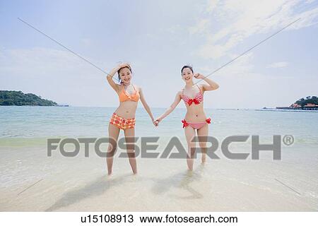 Two young women in bikini holding hands View Large Photo Image Stock Image - Two young women in bikini holding hands. Fotosearch