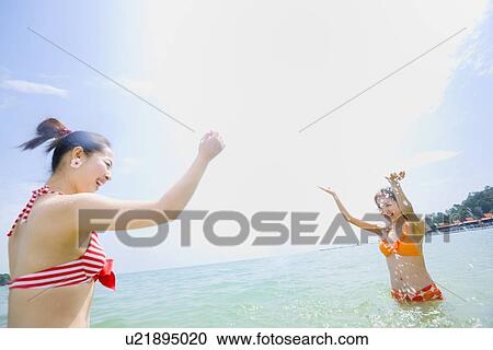 Two young women in bikini splashing water View Large Photo Image Stock Image - Two young women in bikini splashing water. Fotosearch