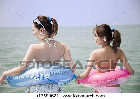 Two young women in bikini standing View Large Photo Image Stock Image - Two young women in bikini standing. Fotosearch
