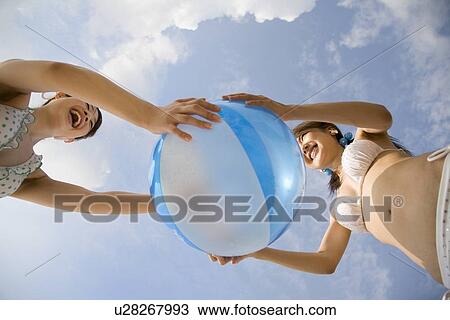 Stock Image - Two young women playing with beach ball. Fotosearch