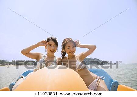 Stock Image - Two young women riding on pedal boat. Fotosearch