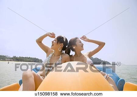 Stock Photo - Two young women riding on pedal boat. Fotosearch