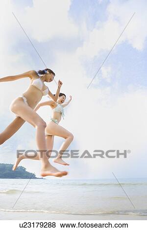 Stock Photo - Two young women running at beach. Fotosearch