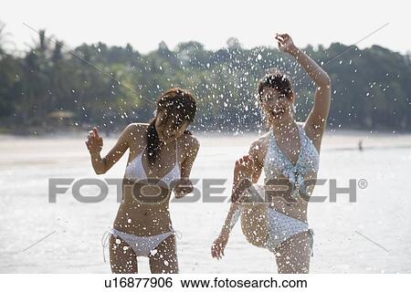 Two young women splashing in water View Large Photo Image Stock Photograph - Two young women splashing in water. Fotosearch