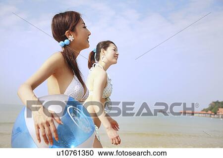 Two young women walking at beach View Large Photo Image Stock Image - Two young women walking at beach. Fotosearch
