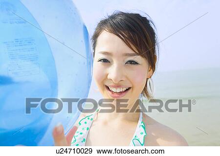 Stock Photo - Young woman holding with beach ball. Fotosearch