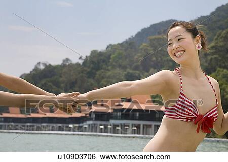 Stock Photograph - Young woman in bikini pulled by hand. Fotosearch