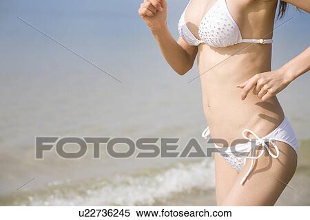 Stock Photography - Young woman in bikini running. Fotosearch