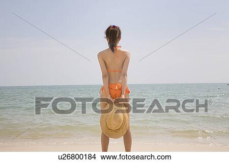 Young woman in bikini standing at beach View Large Photo Image Picture - Young woman in bikini standing at beach. Fotosearch
