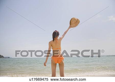 Young woman in bikini standing at beach View Large Photo Image Stock Photography - Young woman in bikini standing at beach. Fotosearch