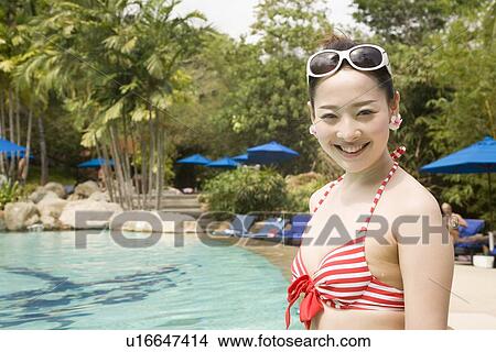 Young woman in bikini standing at poolside View Large Photo Image Picture - Young woman in bikini standing at poolside. Fotosearch