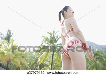 Stock Image - Young woman in bikini standing. Fotosearch