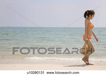 Young woman in bikini walking at beach View Large Photo Image Stock Image - Young woman in bikini walking at beach. Fotosearch