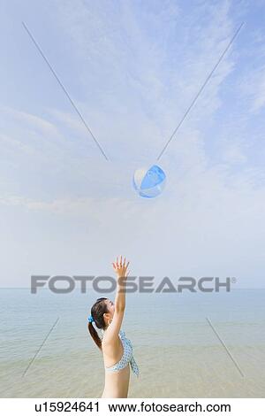 Stock Image - Young woman playing with beach ball. Fotosearch