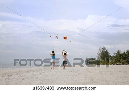 Stock Image - Two young women throwing flip flop and hat. Fotosearch