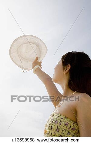 Stock Photo - Young woman holding hat. Fotosearch