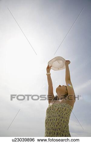 Stock Photograph - Young woman holding hat. Fotosearch