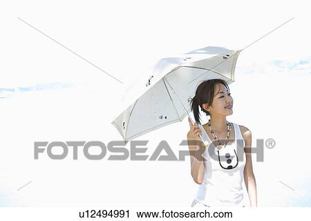 Stock Image - Young woman holding parasol. Fotosearch