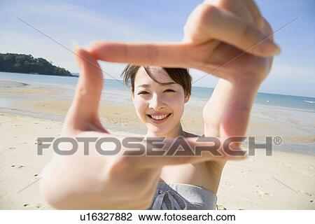 Stock Image - Young woman making frame with hands. Fotosearch