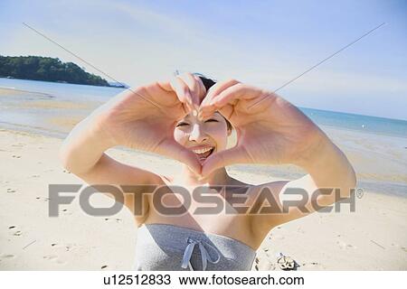 Young woman making heart shape with hands View Large Photo Image Stock Image - Young woman making heart shape with hands. Fotosearch