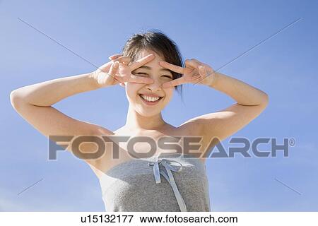 Stock Photo - Young woman making peace sign. Fotosearch