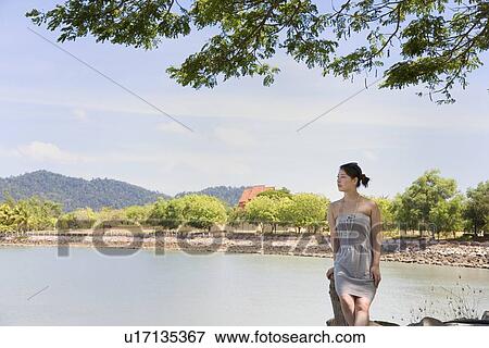 Young woman sitting at beach View Large Photo Image Stock Photo - Young woman sitting at beach. Fotosearch