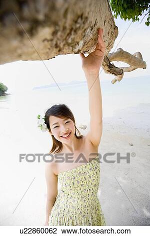Stock Image - Young woman standing at beach. Fotosearch