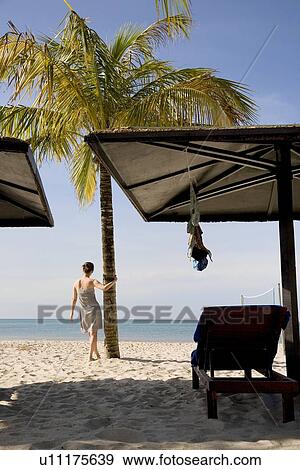 Young woman standing at beach View Large Photo Image Stock Photo - Young woman standing at beach. Fotosearch