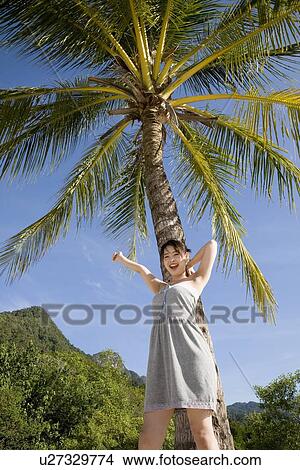 Young woman standing in front of palm tree View Large Photo Image Picture - Young woman standing in front of palm tree. Fotosearch