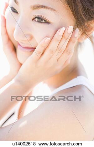 Young woman touching cheek View Large Photo Image Stock Photo - Young woman touching cheek. Fotosearch