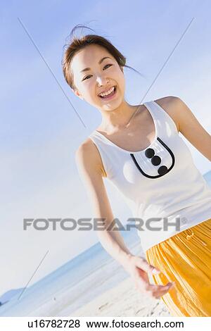 Stock Photo - Young woman walking at beach. Fotosearch