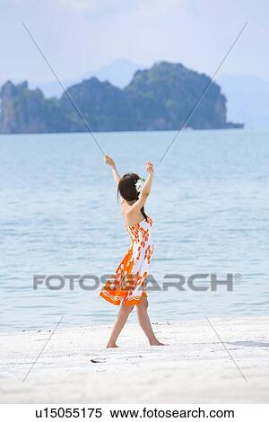 Stock Photography - Young woman walking at beach. Fotosearch