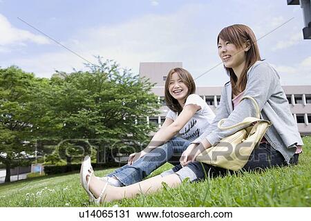 Stock Image - Young women sitting on lawn. Fotosearch