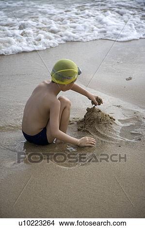 Picture - A boy is playing the sand on the beach. Fotosearch