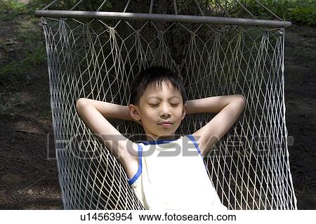 Picture - A boy lying on the hammock, taking a nap. Fotosearch