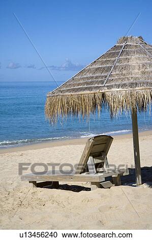 A thatched sunshade and a lounge chair on the beach View Large Photo Image Stock Image - A thatched sunshade and a lounge chair on the beach. Fotosearch