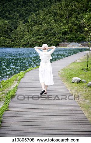 A woman walking on the boardwalk by a lake View Large Photo Image Stock Photo - A woman walking on the boardwalk by a lake. Fotosearch