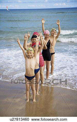 Stock Image - Children standing on the beach and smiling happily with arms stretched. Fotosearch