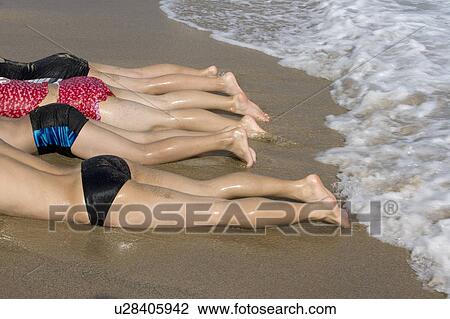 Stock Image - Four people lying on the beach. Fotosearch