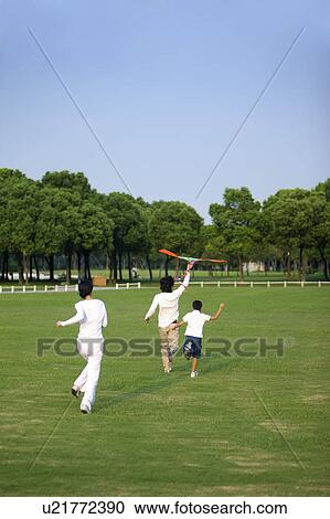 Family with one child flying a kite on the lawn View Large Photo Image Stock Image - Family with one child flying a kite on the lawn. Fotosearch