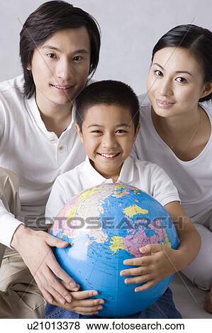 Family with one child looking at the camera and holding the globe View Large Photo Image Stock Photo - Family with one child looking at the camera and holding the globe. Fotosearch