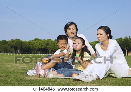 Family with two children blowing bubbles on the lawn View Large Photo Image Stock Photography - Family with two children blowing bubbles on the lawn. Fotosearch