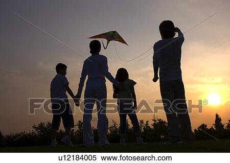 Stock Photography - Family with two children flying a kite at sunset. Fotosearch