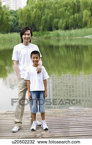 Father and son standing by lake View Large Photo Image Stock Image - Father and son standing by lake. Fotosearch