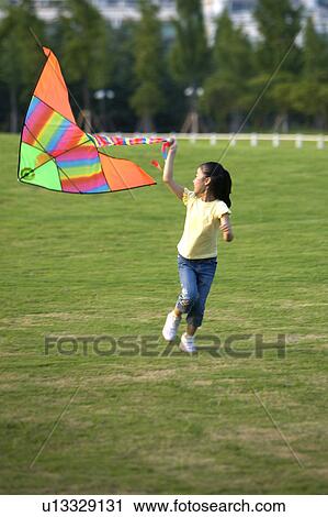 Stock Image - Little girl flying a kite on the lawn. Fotosearch