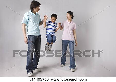 Stock Image - The young parents lifting up their son. Fotosearch