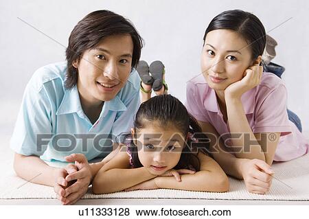 Stock Photo - Young family with daughter lying on front and looking at the camera. Fotosearch