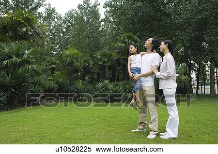 Young family with daughter standing on the lawn and looking away View Large Photo Image Stock Photography - Young family with daughter standing on the lawn and looking away. Fotosearch