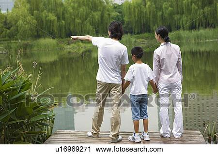 Young family with son standing near the lakeside View Large Photo Image Stock Image - Young family with son standing near the lakeside. Fotosearch