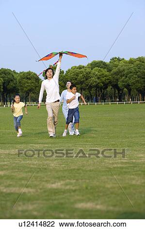 Young family with two children flying a kite on the lawn View Large Photo Image Stock Image - Young family with two children flying a kite on the lawn. Fotosearch